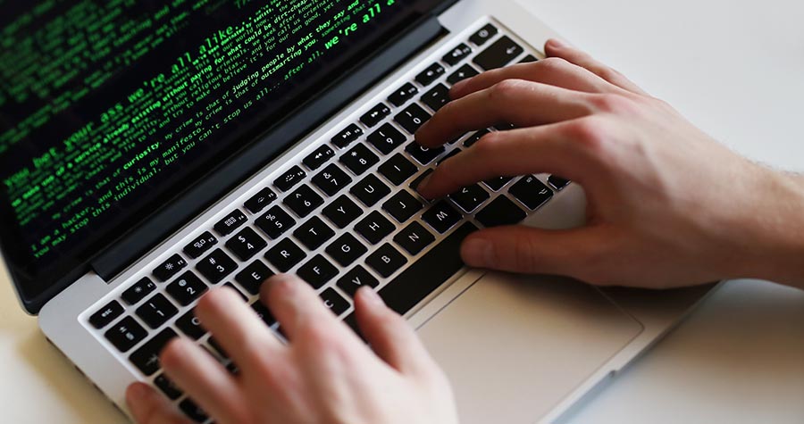 mão digitando em um laptop realizando um cyber ataque